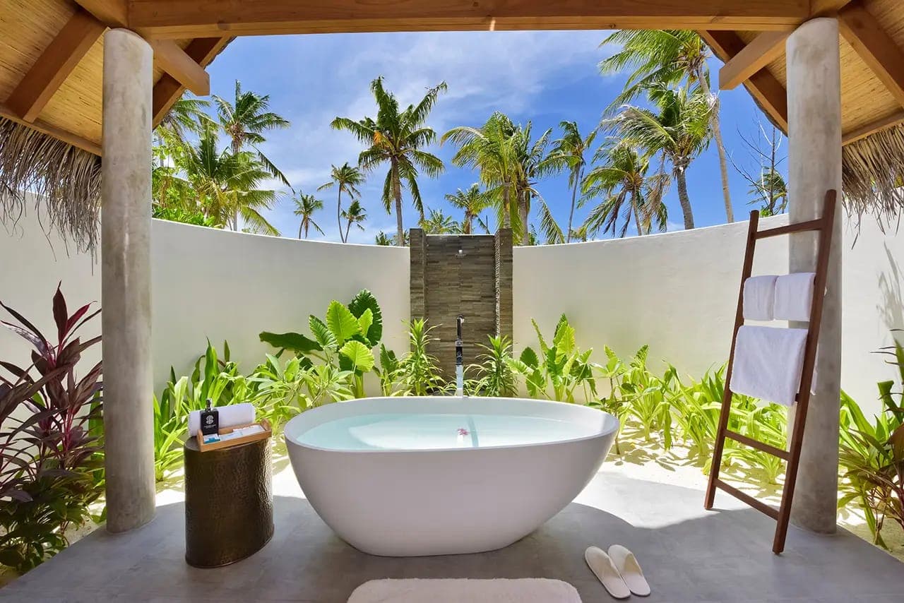 Baño exterior con bañera y palmeras